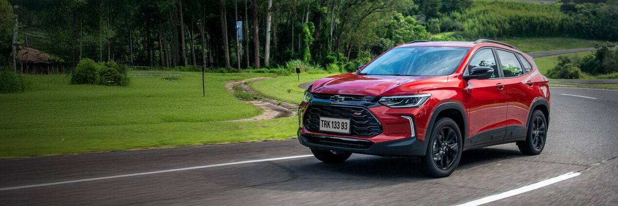 Chevrolet Tracker roja en camino con árboles al costado