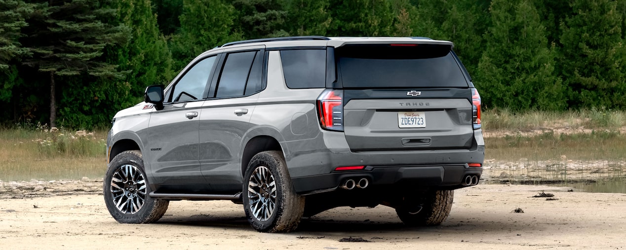 Vista trasera de la Chevrolet Tahoe 2025 Z71 en color blanco, en terreno off-road junto a un bosque
