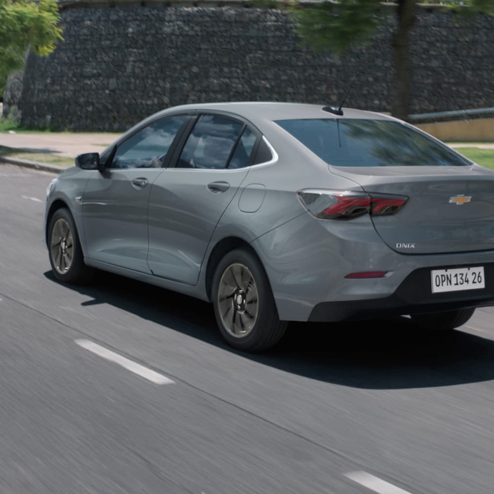 Vista trasera del Chevrolet Onix Plus conduciendo en camino urbano