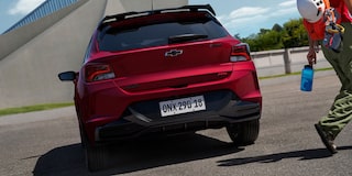 Vista trasera del Chevrolet Onix 2026 color rojo Jinx estacionado en área urbana