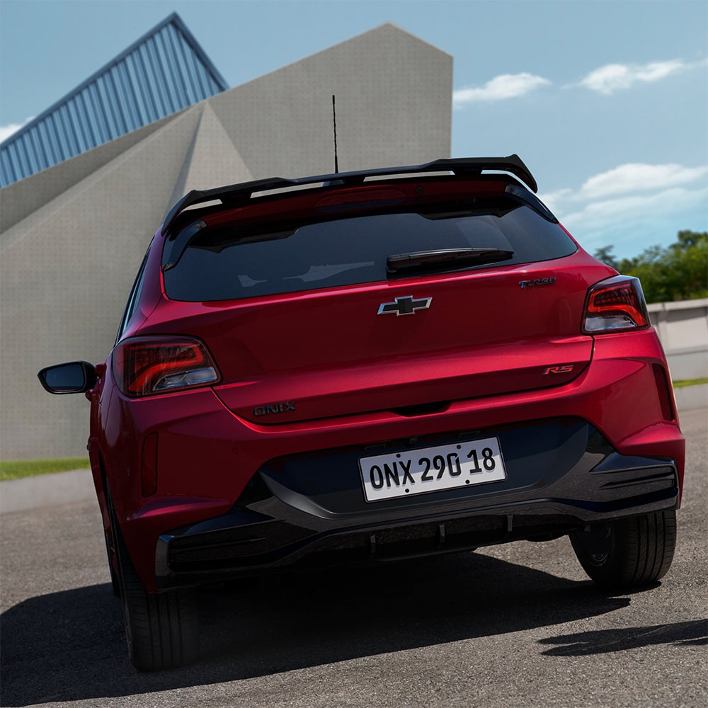 Vista trasera del Chevrolet Onix 2026 color rojo Jinx estacionado en área urbana