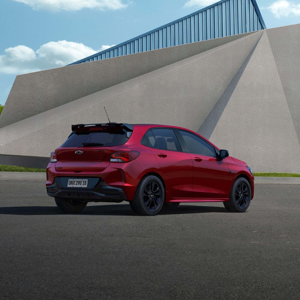 Vista trasera lateral del Onix 2026 color Rojo Jinx estacionado en área urbana