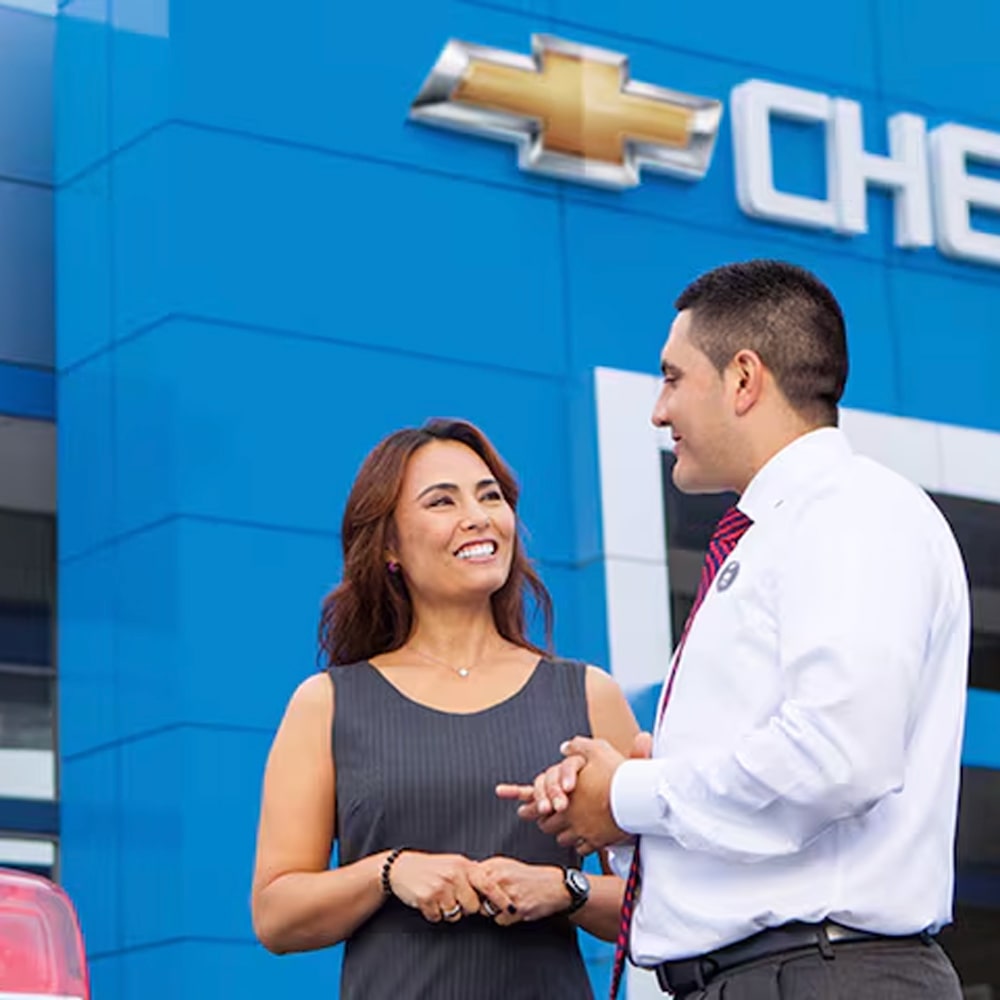 Cliente feliz recibiendo atención personalizada para comprar su Chevrolet en concesionario oficial.